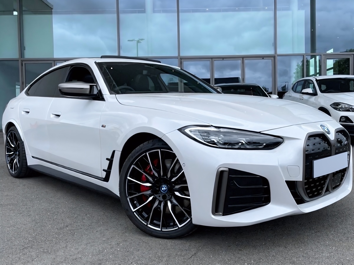 A front three quarters view of a 2024 BMW i4 M50 parked in front of a dealership