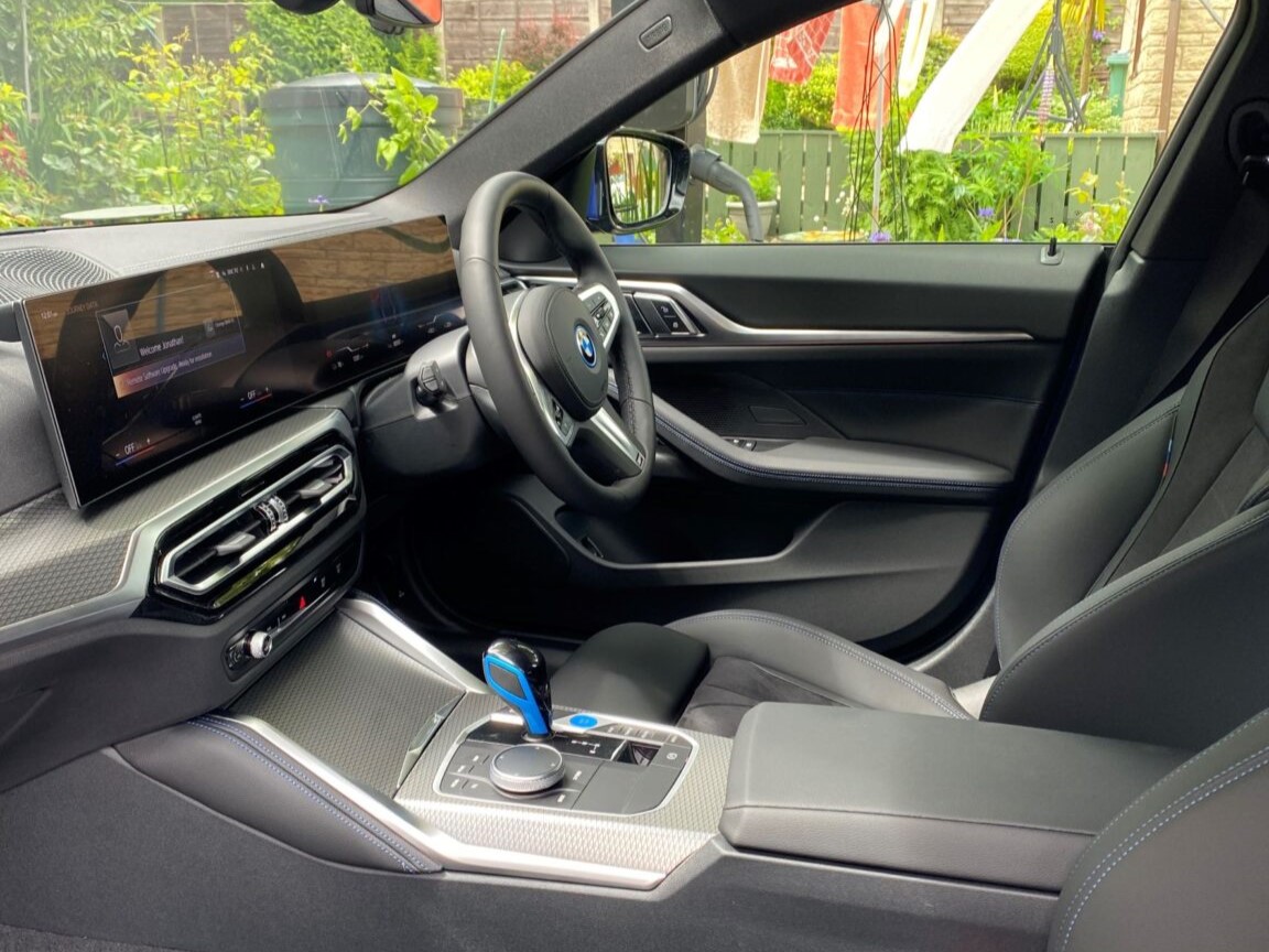 BMW i4 dashboard featuring the curved infotainment screen, digital instrument cluster, and rotary iDrive controller on the centre console