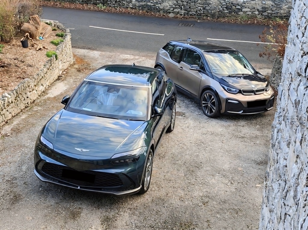 A Genesis GV60 and a BMW i3 parked on a driveway