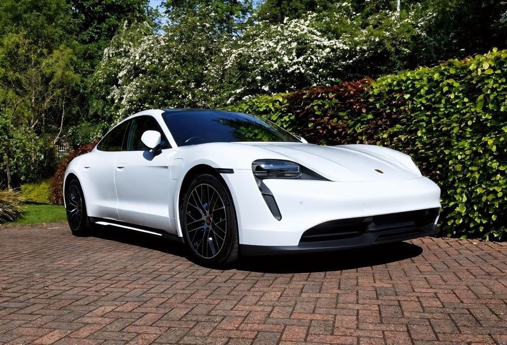 A white Porsche Taycan parked on an owner's driveway